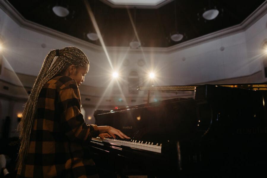 亩ic student plays the piano in an auditorium.